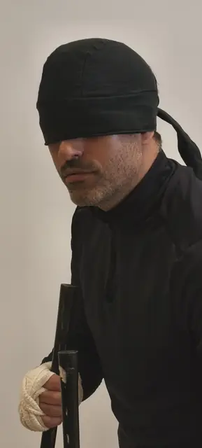 Personaje de negro con los ojos vendados y un bastón